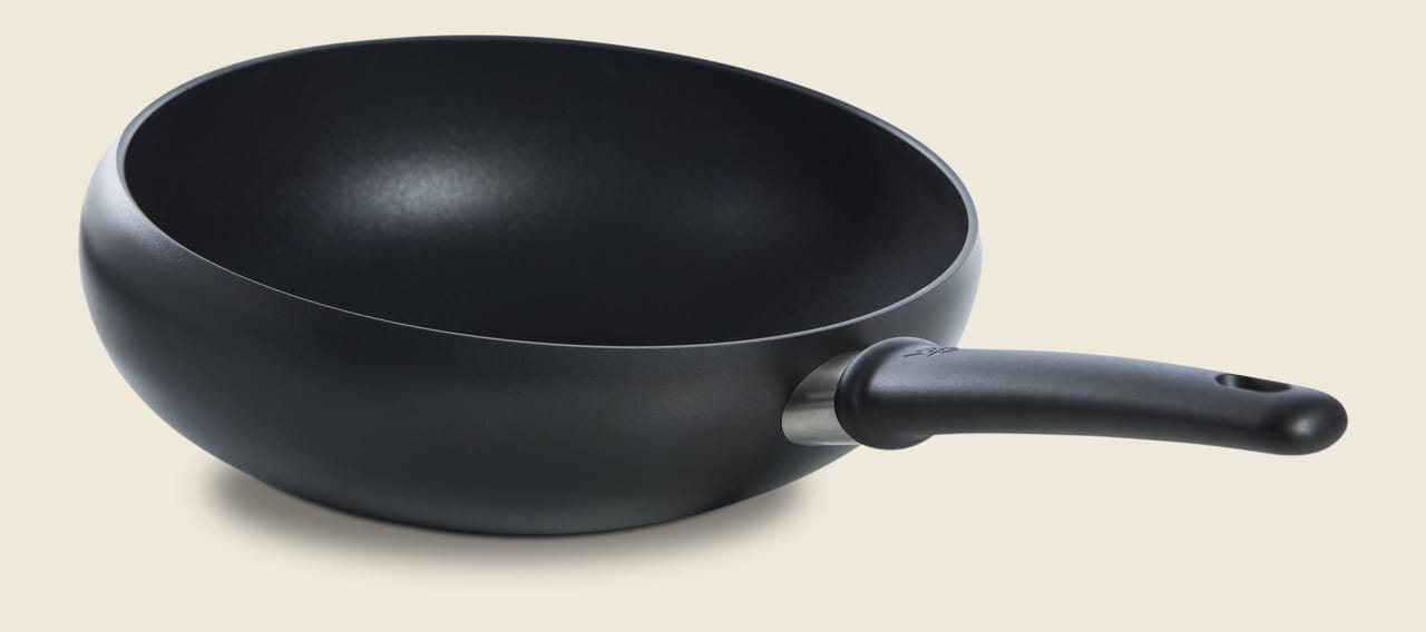 Black cast iron skillet with poured edge and stay-cool handle, 28 cm